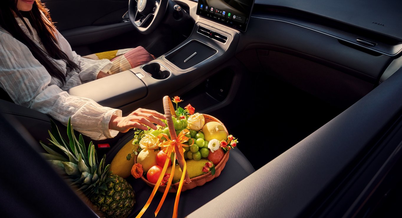 A woman sitting in the driver's seat with fresh fruit beside her, showcasing the healthy cabin