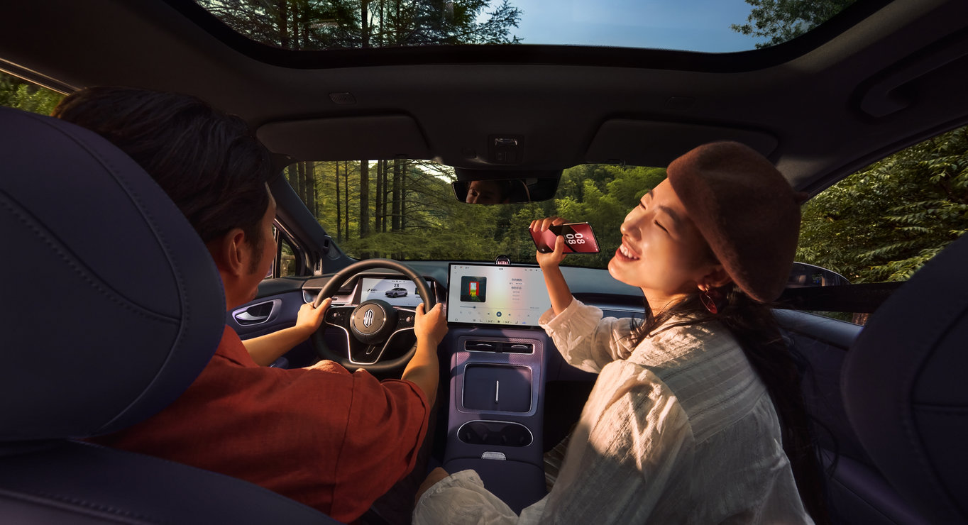 A man and a woman doing mic-free karaoke inside the car