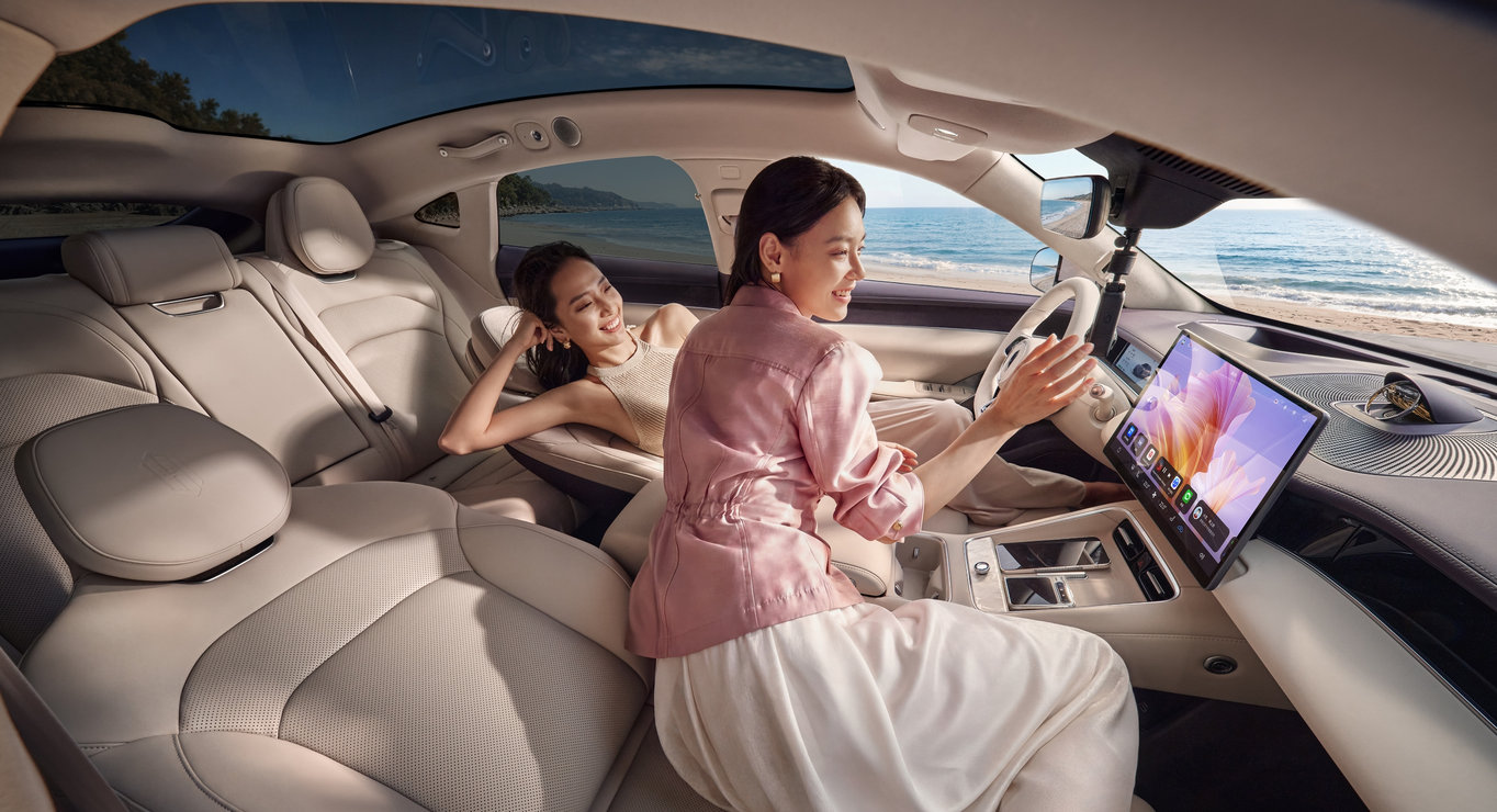 A user reclining in the Shangjie Z7-Z7T, showing the car's zero-gravity seats.