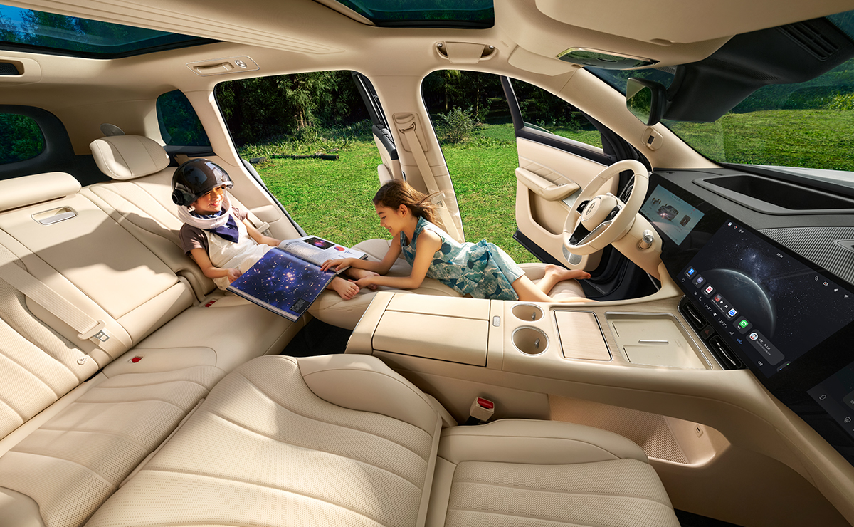 A family of three sitting together on the second-row seats of the AITO M8 in White Sand Apricot with the front seats folded