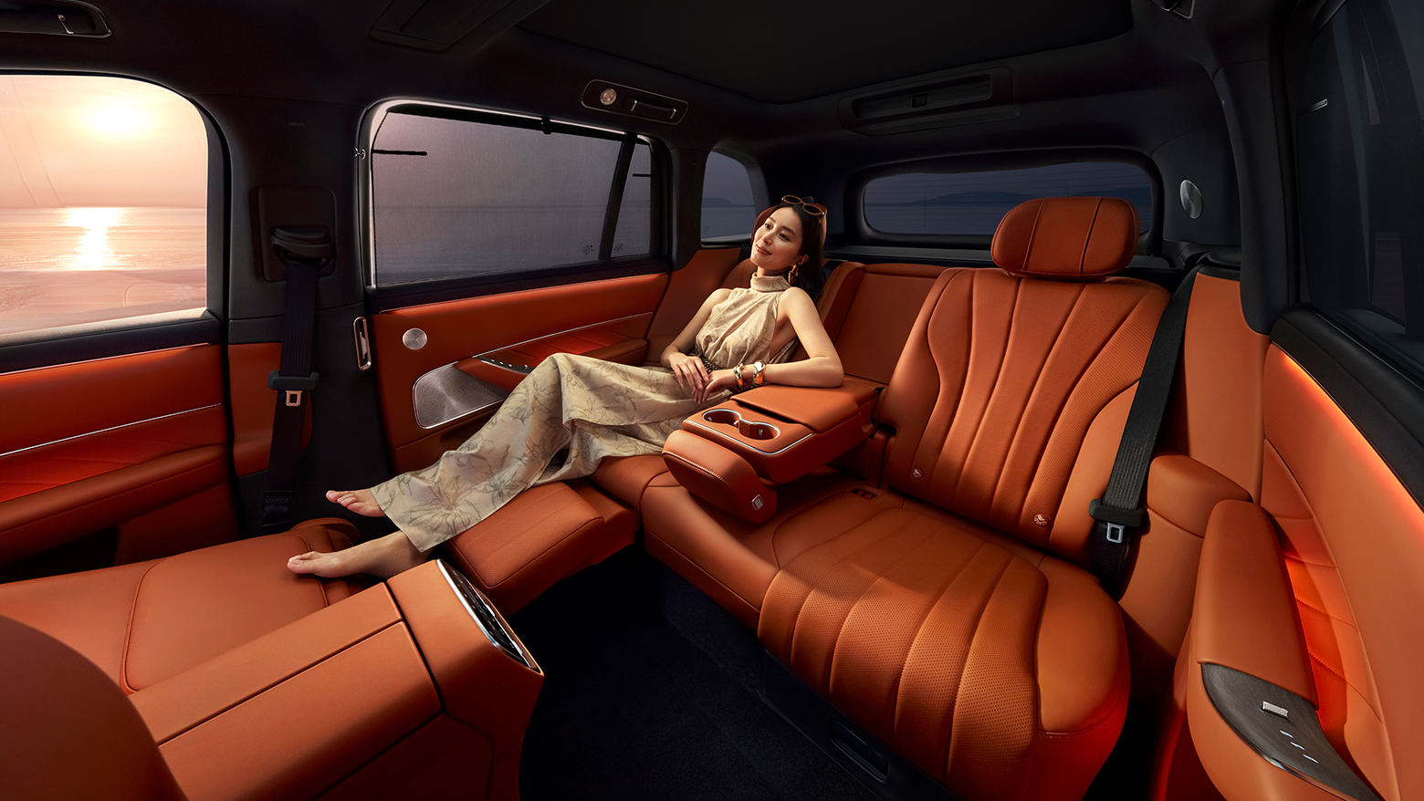 A woman lying on the unfolded second-row zero-gravity seat of the AITO M8 in Russet Orange