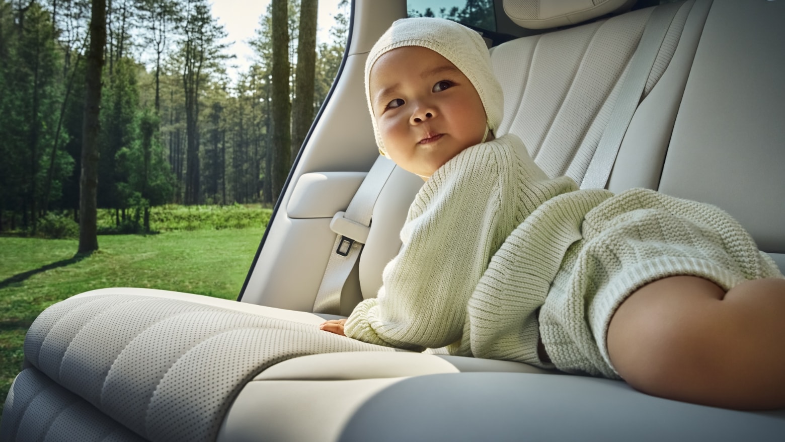 A baby lying on the rear seat of the AITO M8 in White Sand Apricot