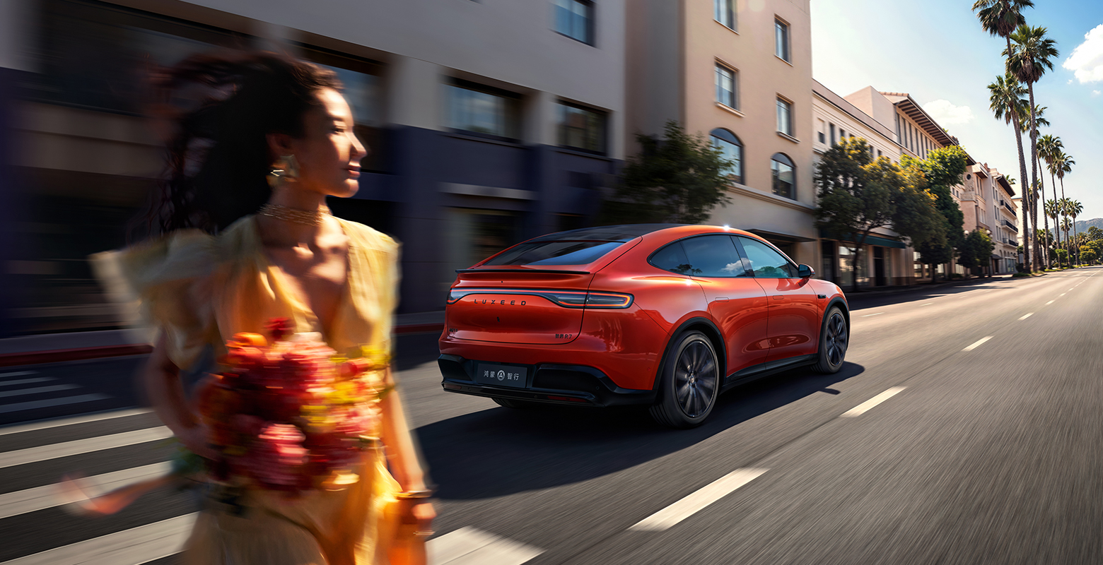 The Luxeed R7 REEV in Vibrant Orange driving on the road, showing its long-range performance